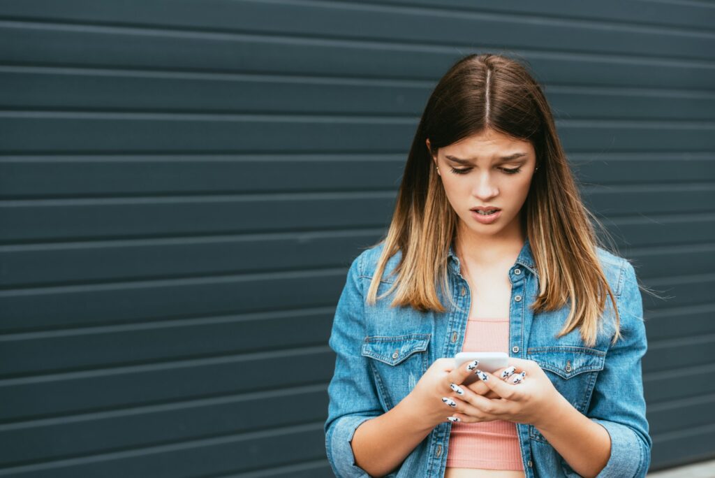 Upset teenager using smartphone near building outdoor