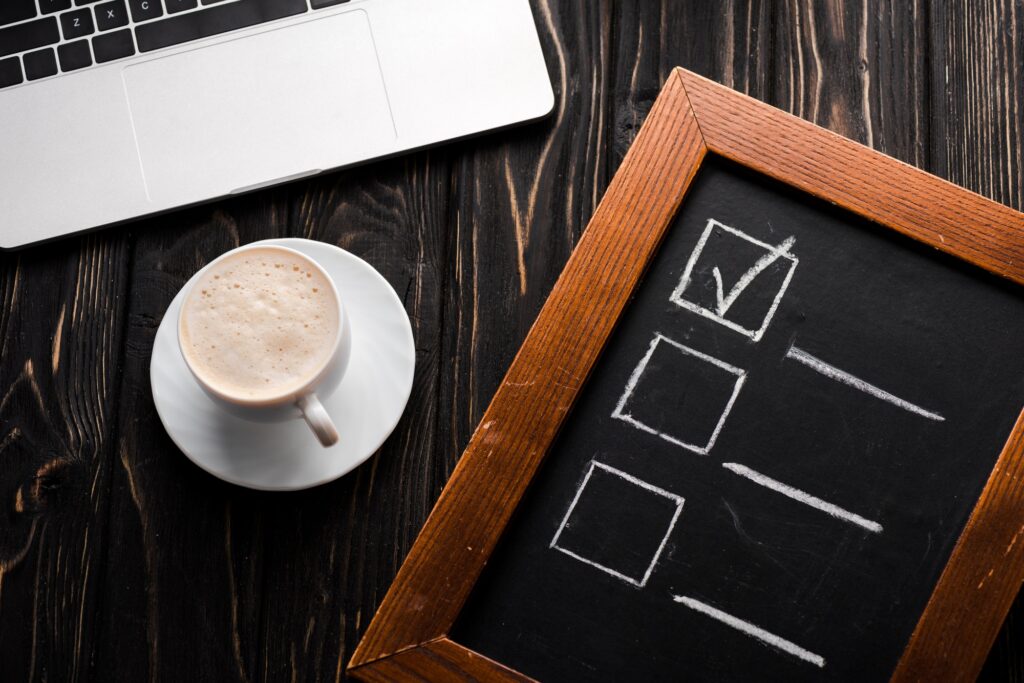 top view of chalk board with checklist near cup of coffee and laptop on table, e-commerce concept