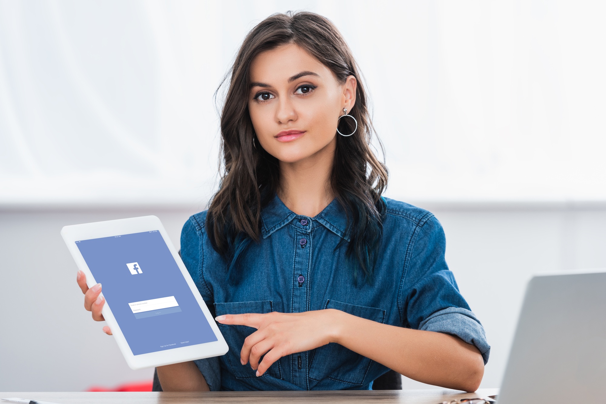 attractive young woman pointing on digital tablet screen with facebook website