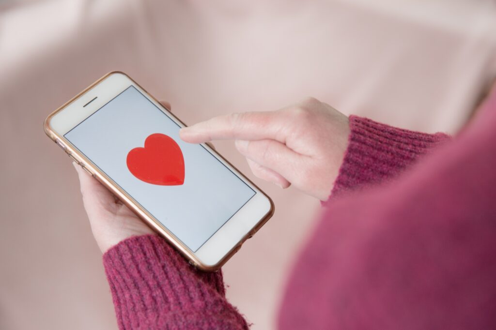 A single girl looking for love by tapping a love heart on her mobile touchscreen online dating app