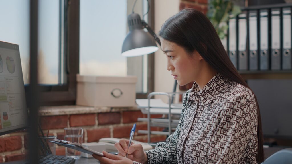 Business woman looking at files on clipboard to work on strategy